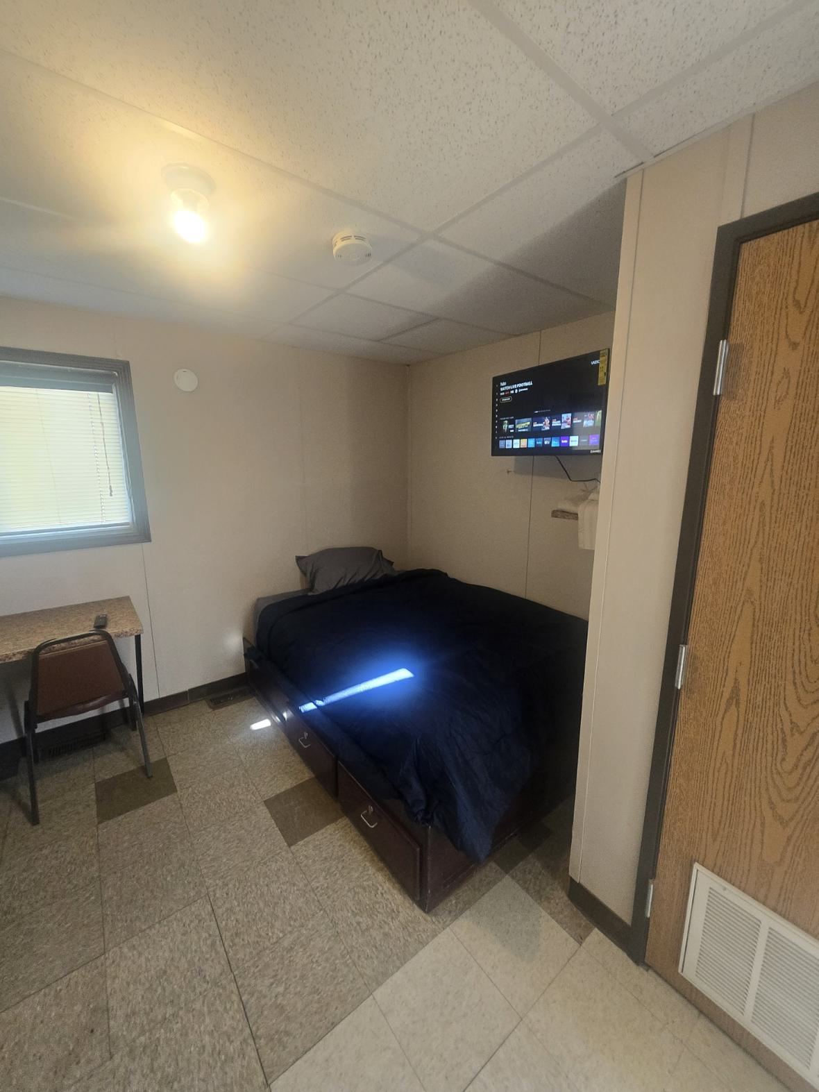 Inside a room — bed, TV and a desk